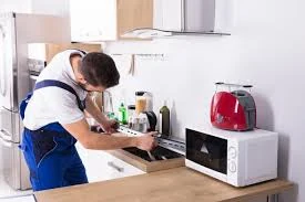 Technician inspecting a countertop microwave in a kitchen
